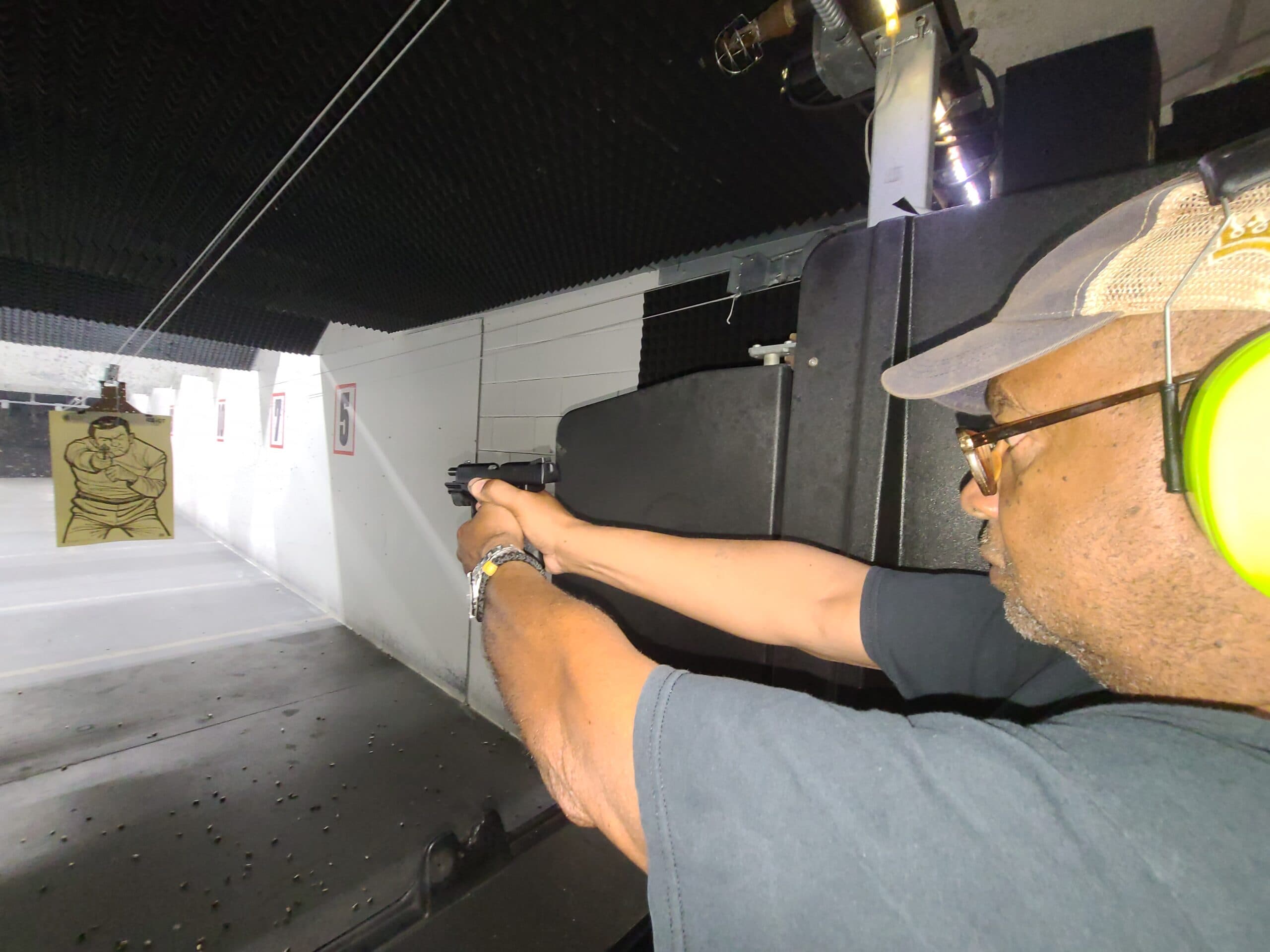 A student training on the firing line at a National Safety Center range, lanes lit downrange